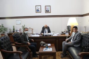 Ege Üniversitesi Rektör yardımcısı Prof. Dr. Hakan Atılgan makamında Ali Aydoğmuş ve Doç Dr. İbrahim Dalbudak misafir koltuklarında oturuyor.